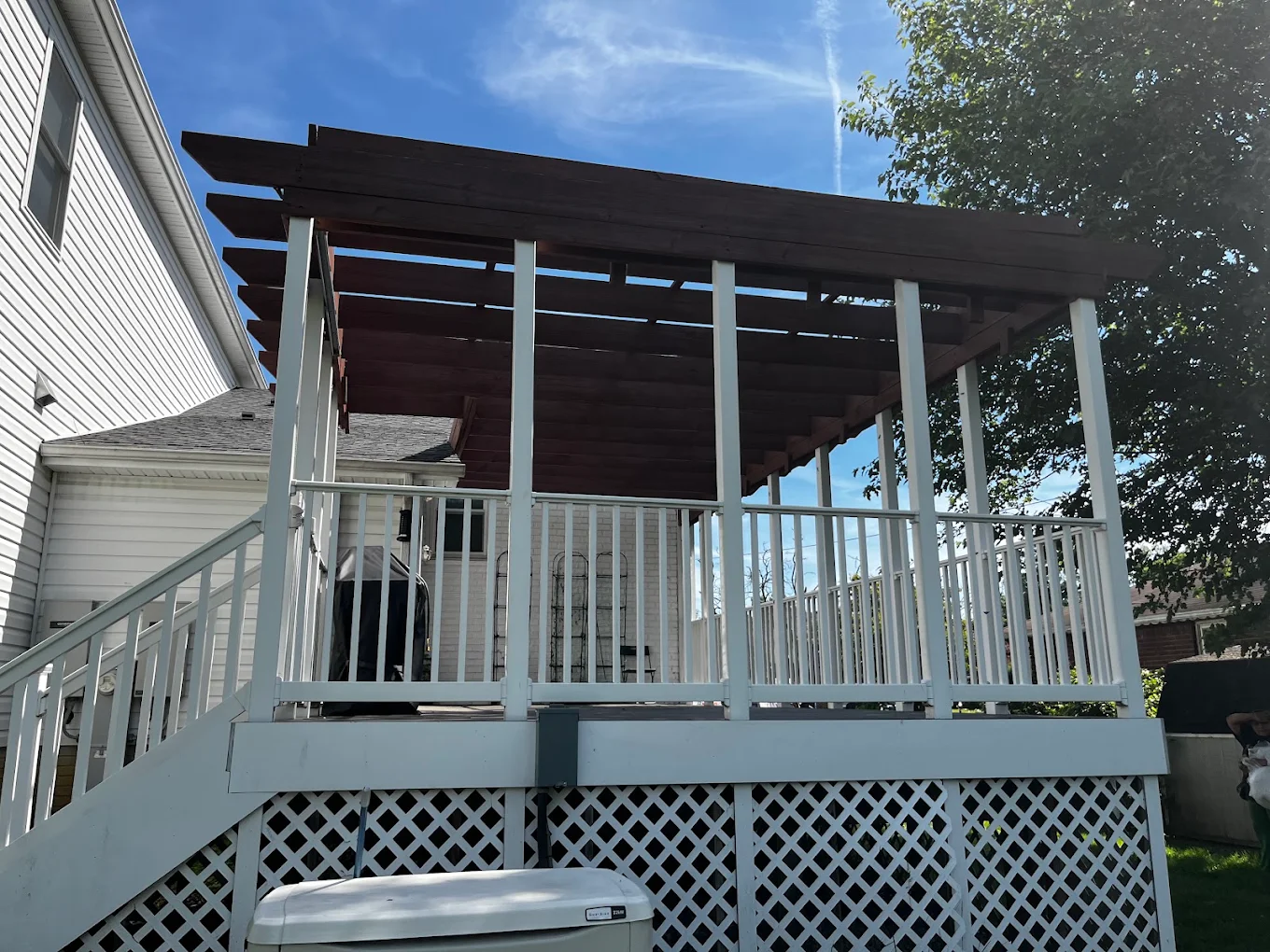 Deck with freshly painted white railings and rich stained pergola beams